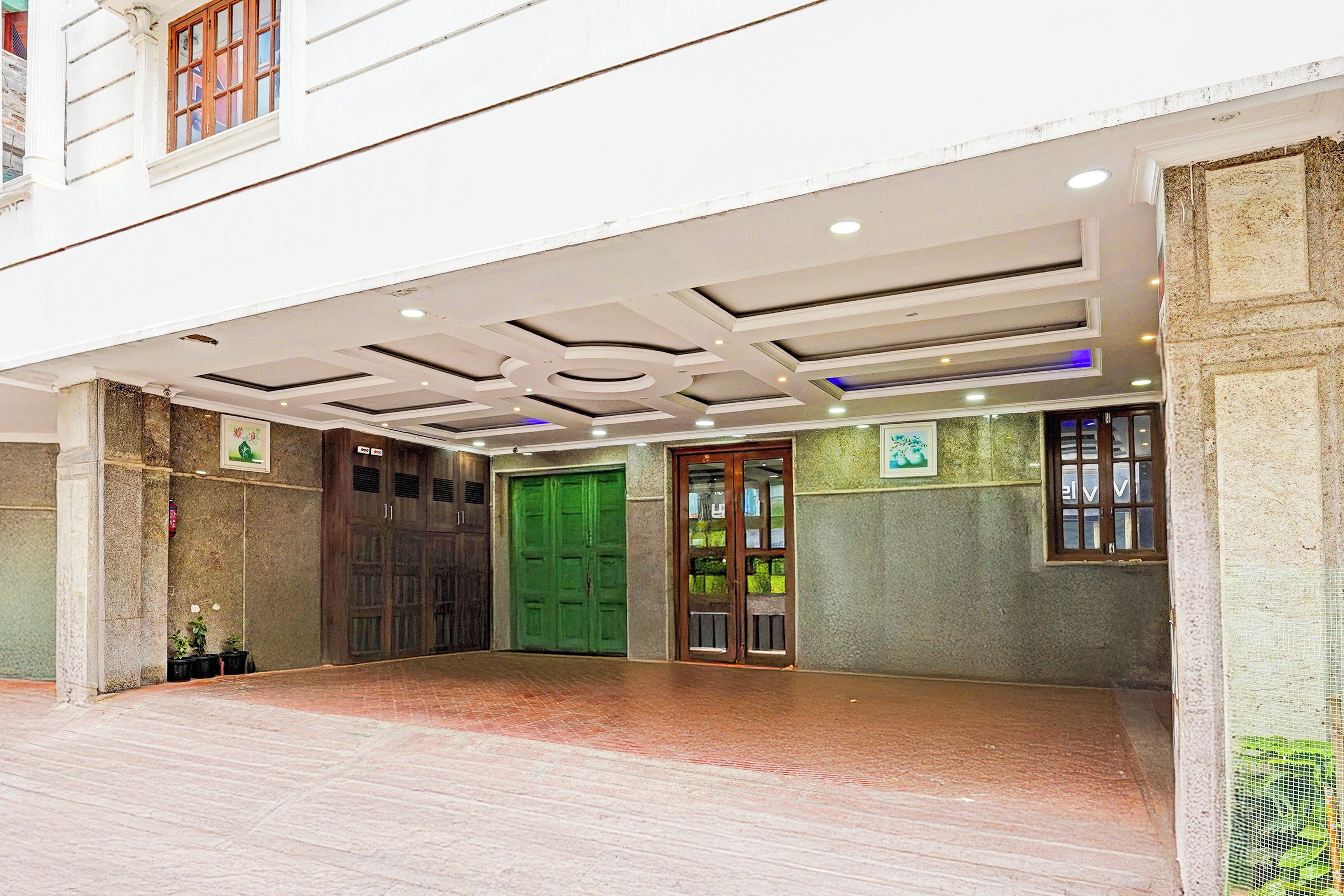 A hotel entrance with a covered walkway, a green door, and a stone wall.