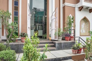 Un edificio de estilo arquitectónico tradicional, con un balcón adornado con macetas y una escalera que conduce a la entrada.