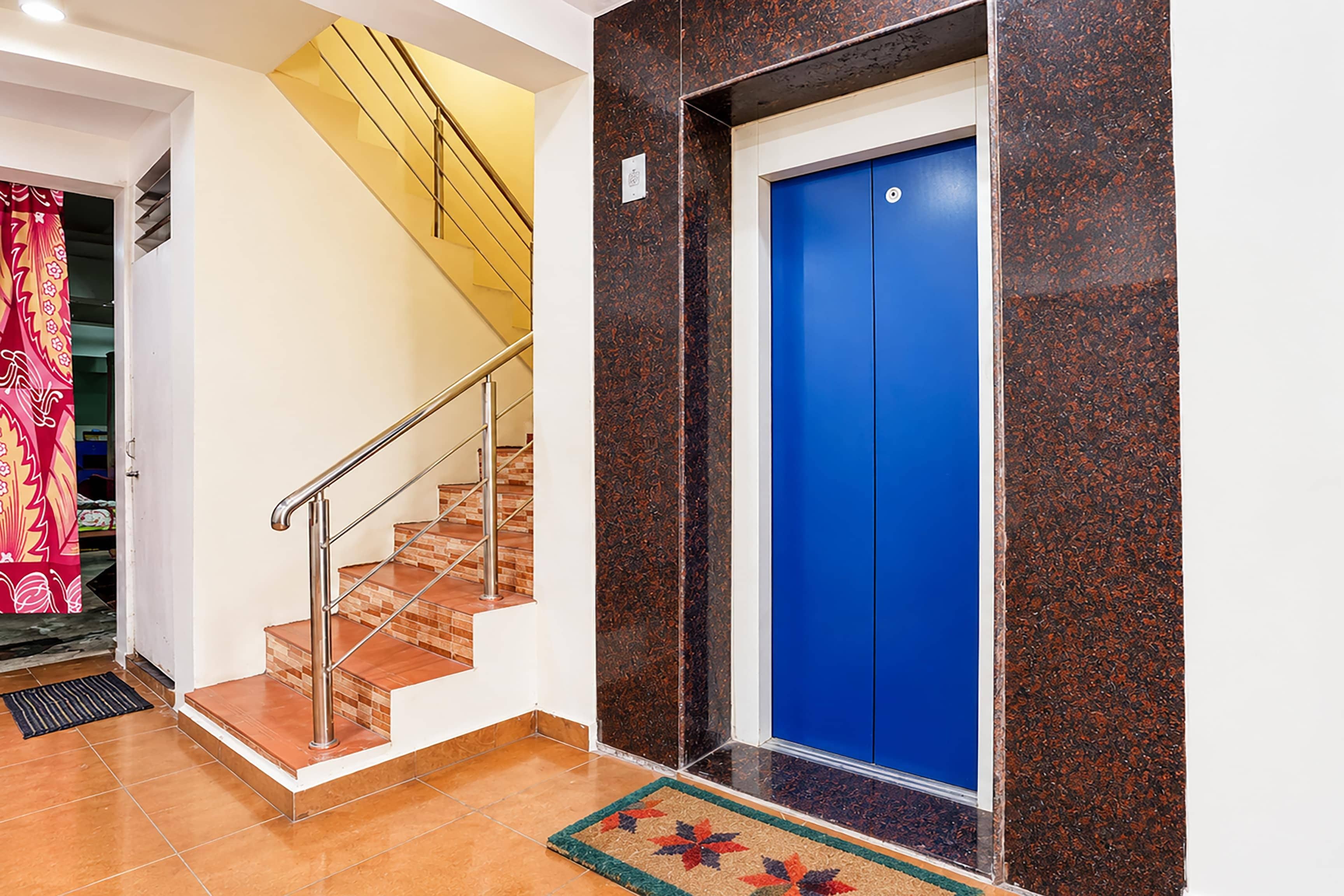 Uma escada com corrimãos de metal que leva a uma porta de elevador azul.