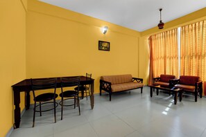 A living room with a dining table, chairs, sofas, and a hanging light fixture. - Collection O KSRTC Bus Station Kottayam (Kottayam)