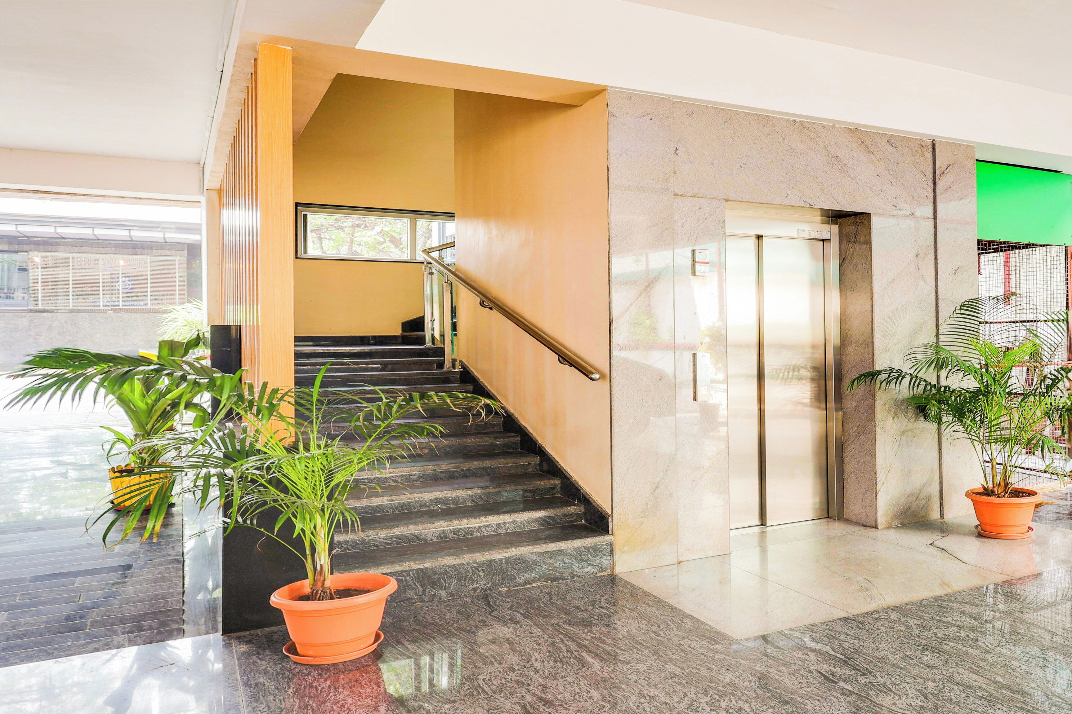 A modern indoor staircase with a handrail, leading to an elevator.