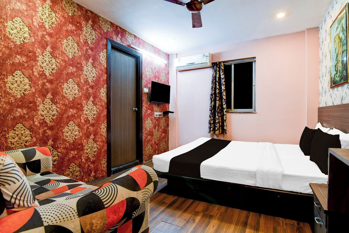 Quarto de hotel com cama, televisão, porta e janela com cortinas.