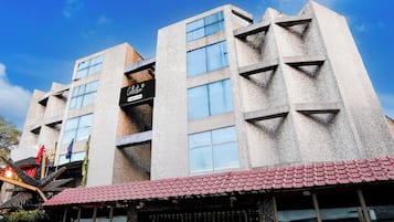 Un edificio de varios pisos con un diseño arquitectónico moderno, que cuenta con ventanas amplias y un revestimiento texturizado.
