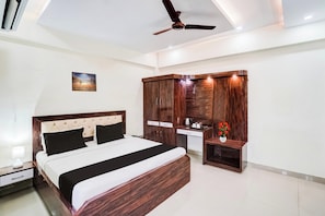 A bedroom with a bed, a wardrobe, a desk, and a ceiling fan. - Hotel O SGPGI (Lucknow)