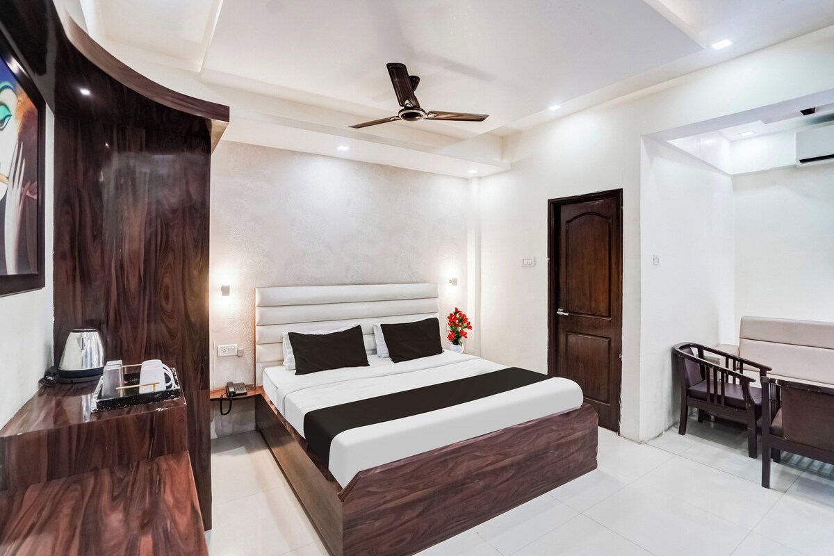 A hotel room with a bed, bedside table, and a desk with a chair.