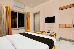 Ein Hotelzimmer mit einem Bett, einem Schreibtisch mit Telefon und Kaffeemaschine, einer Klimaanlage, einem Fernseher und einem Kleiderschrank.