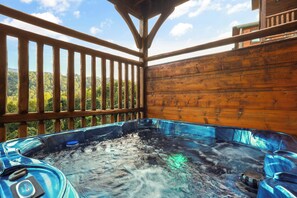 A hot tub with a wooden deck and a view of a forested landscape. - Sleeps 14, Home Theater, Game Room, Hot Tub, Mountain Views (Gatlinburg)