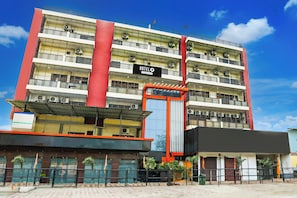 Un hotel de varios pisos con una fachada llamativa de rojo y blanco, balcones en cada nivel y un letrero que indica que es un hotel.