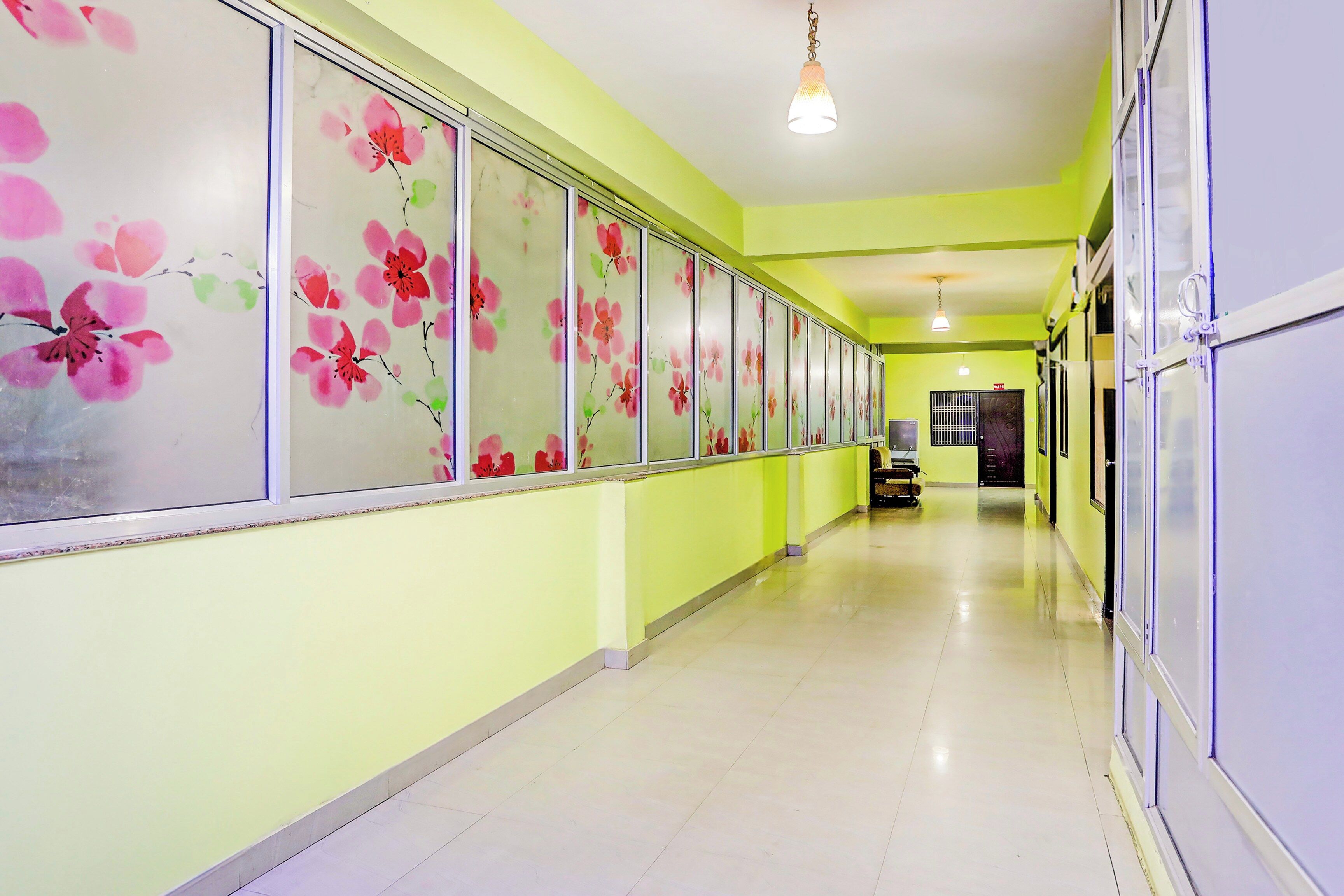 A hallway with a series of doors on one side, a tiled floor, and a hanging light fixture.