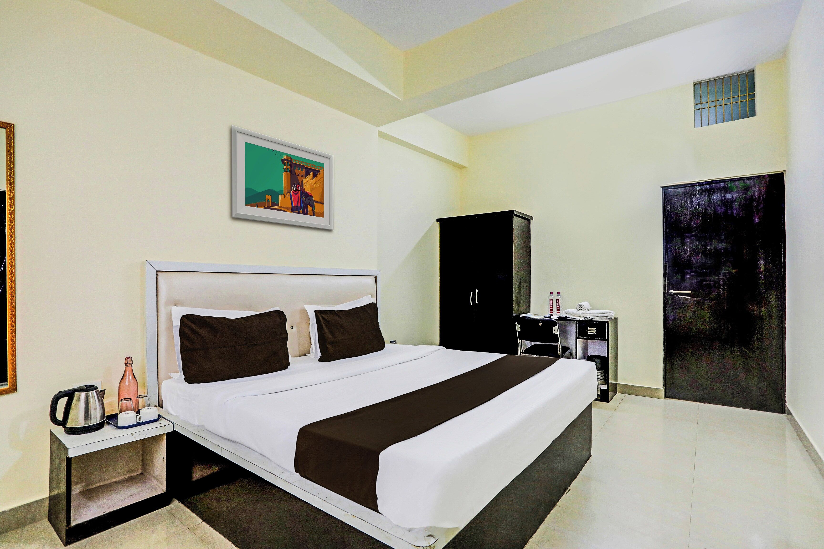 Una habitación de hotel con una cama grande, una mesita de noche, un armario y una puerta.