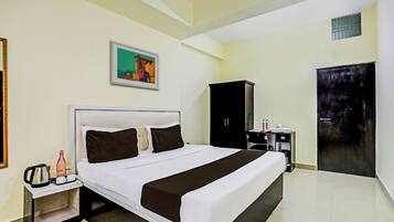 Una habitación de hotel con una cama grande, una mesita de noche, un armario y una puerta.
