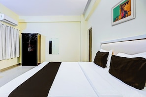 Ein Hotelzimmer mit einem großen Bett, einem Schrank, einem Spiegel und einem Gemälde an der Wand.
