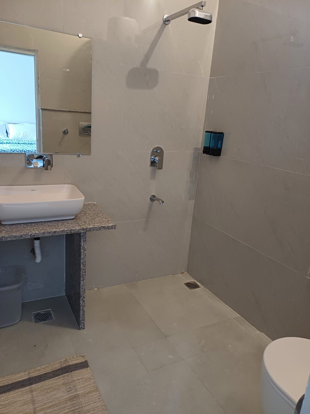 A bathroom with a sink, mirror, shower, and toilet.