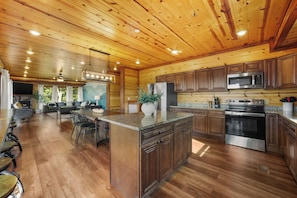 A spacious kitchen with wooden cabinets, a granite countertop, and stainless steel appliances. - Sleeps 36, Private Indoor Pool, Theater, Arcade, Hot Tub, 11 Mi to Dollywood (Sevierville)
