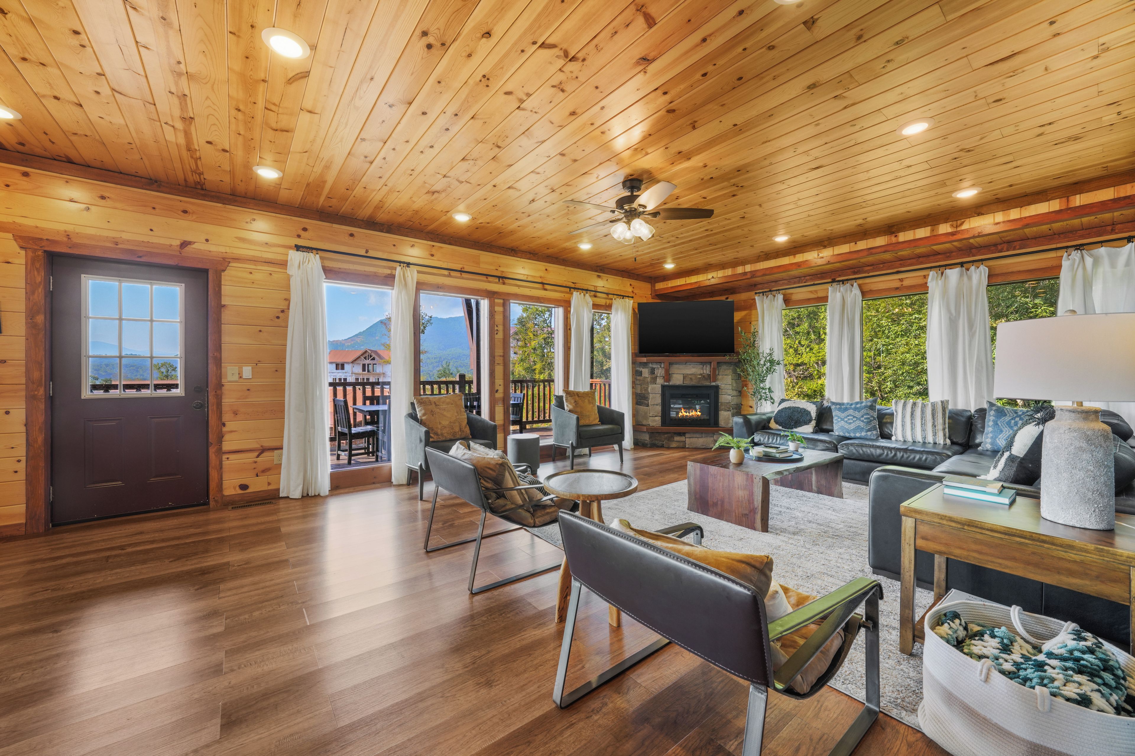 Un vaste espace de vie doté d’une cheminée, de parquets en bois et d’un balcon offrant une vue sur les montagnes.