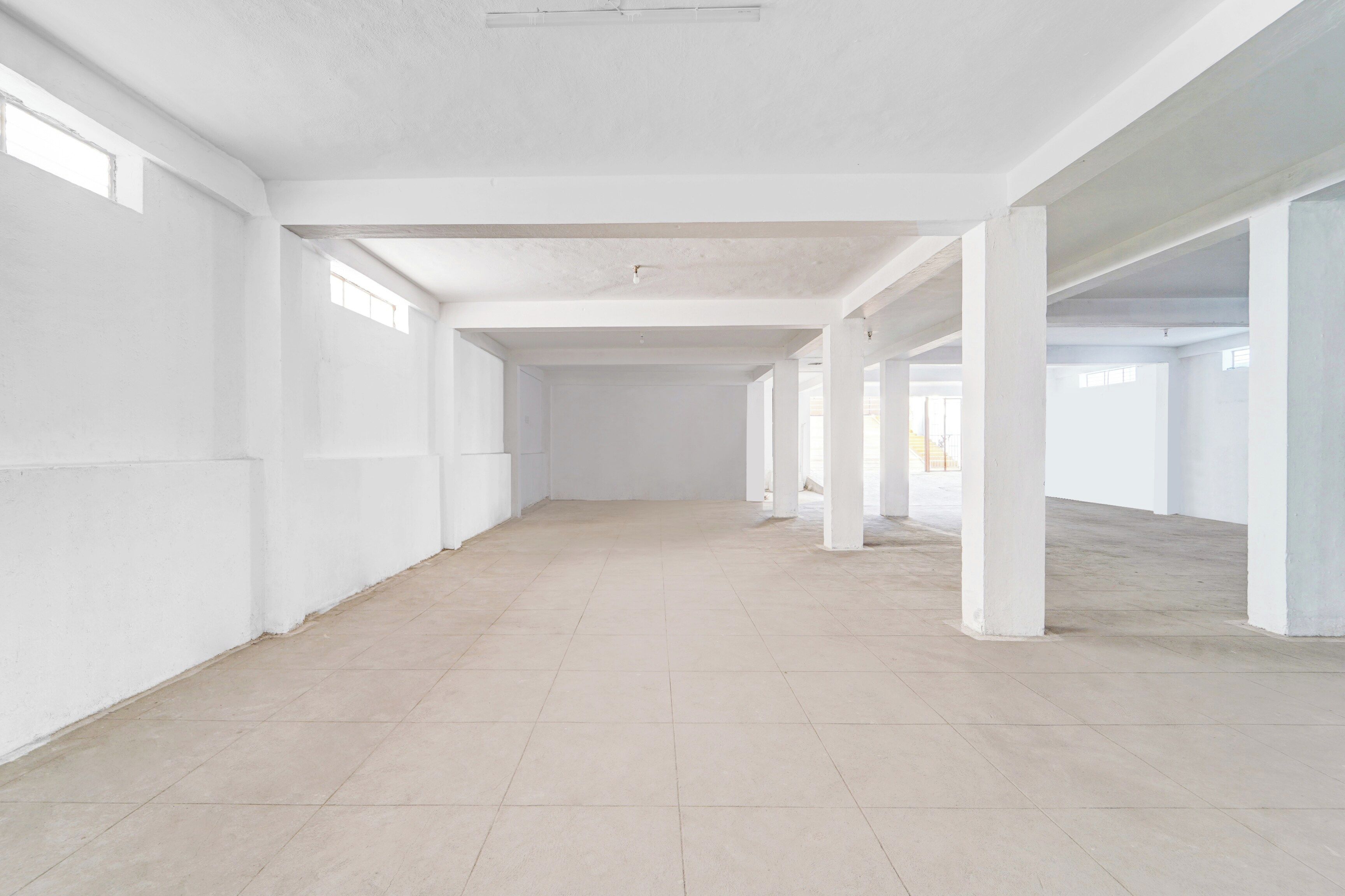 A spacious, empty interior with high ceilings and large windows.