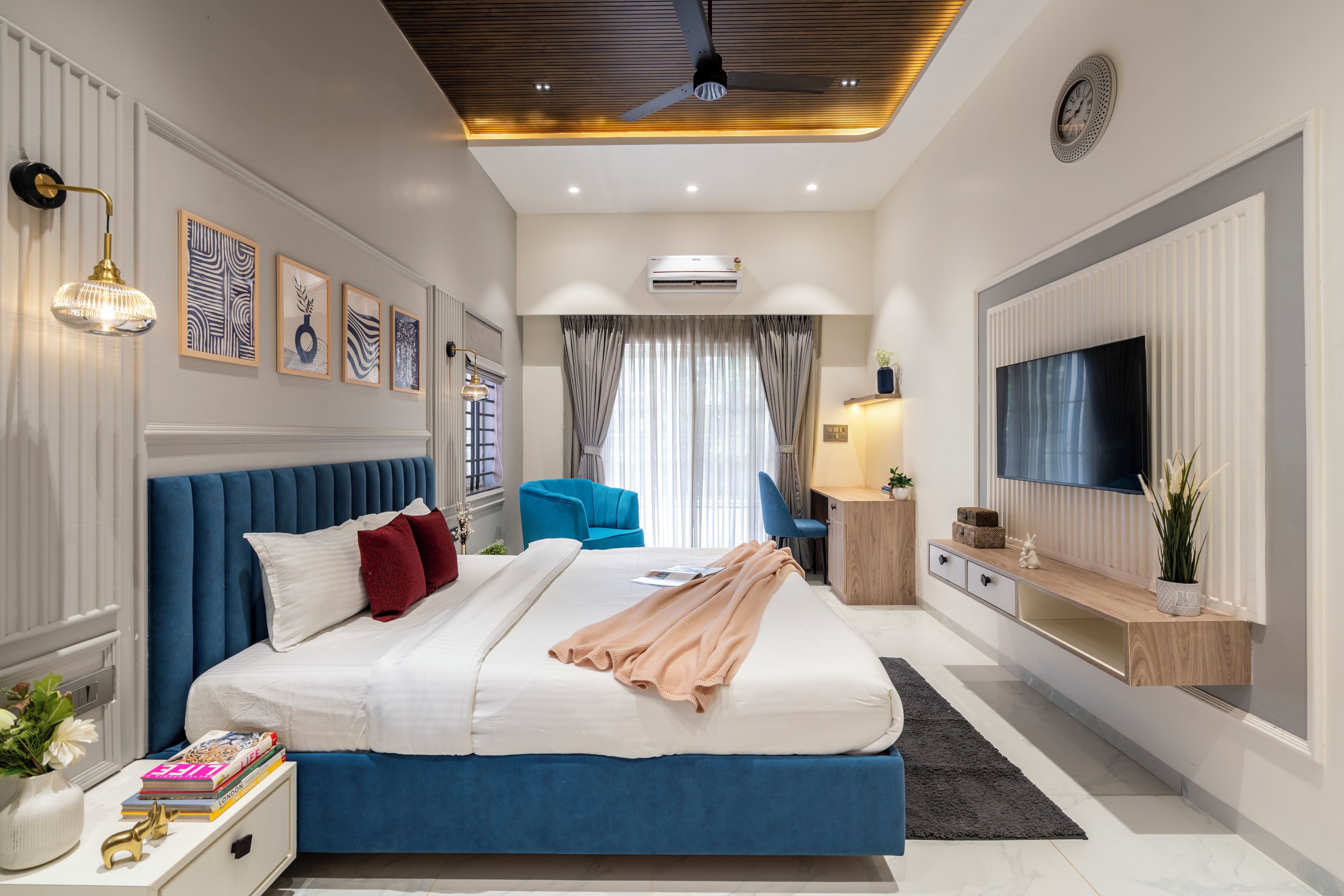 Un dormitorio moderno con una cama grande, un televisor y un ventilador de techo.