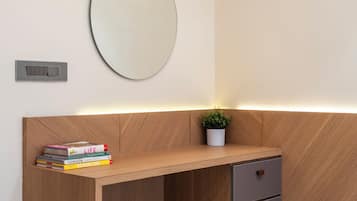 A modern bathroom with a wooden vanity, a round mirror, and a small potted plant.