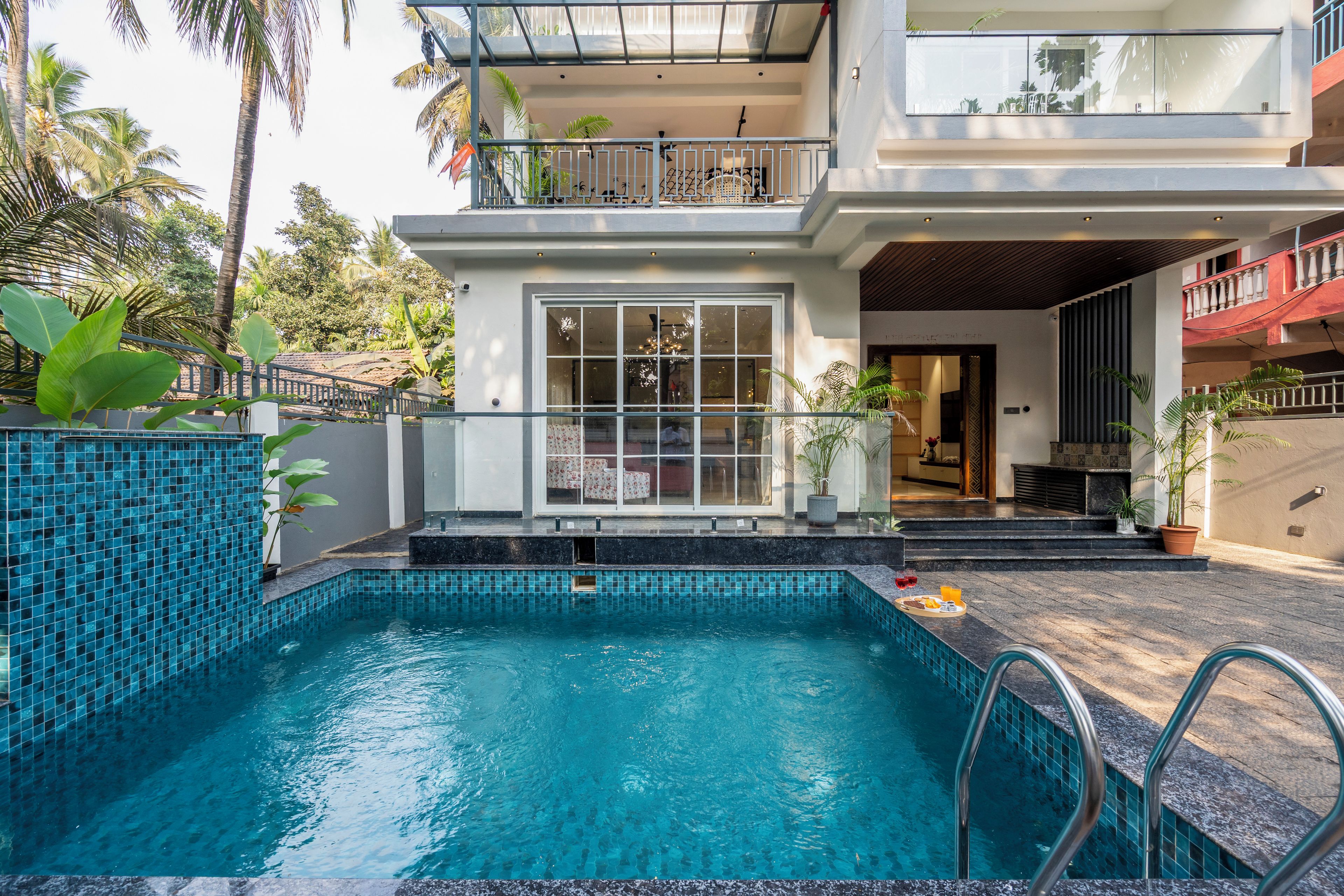 Un edificio residencial con piscina, un balcón con barandilla y plantas en macetas.