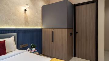 A bedroom with a bed, a wardrobe, a nightstand, a lamp, and a door.