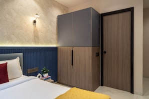 Une chambre à coucher avec un lit, une armoire, une table de chevet, une lampe et une porte.