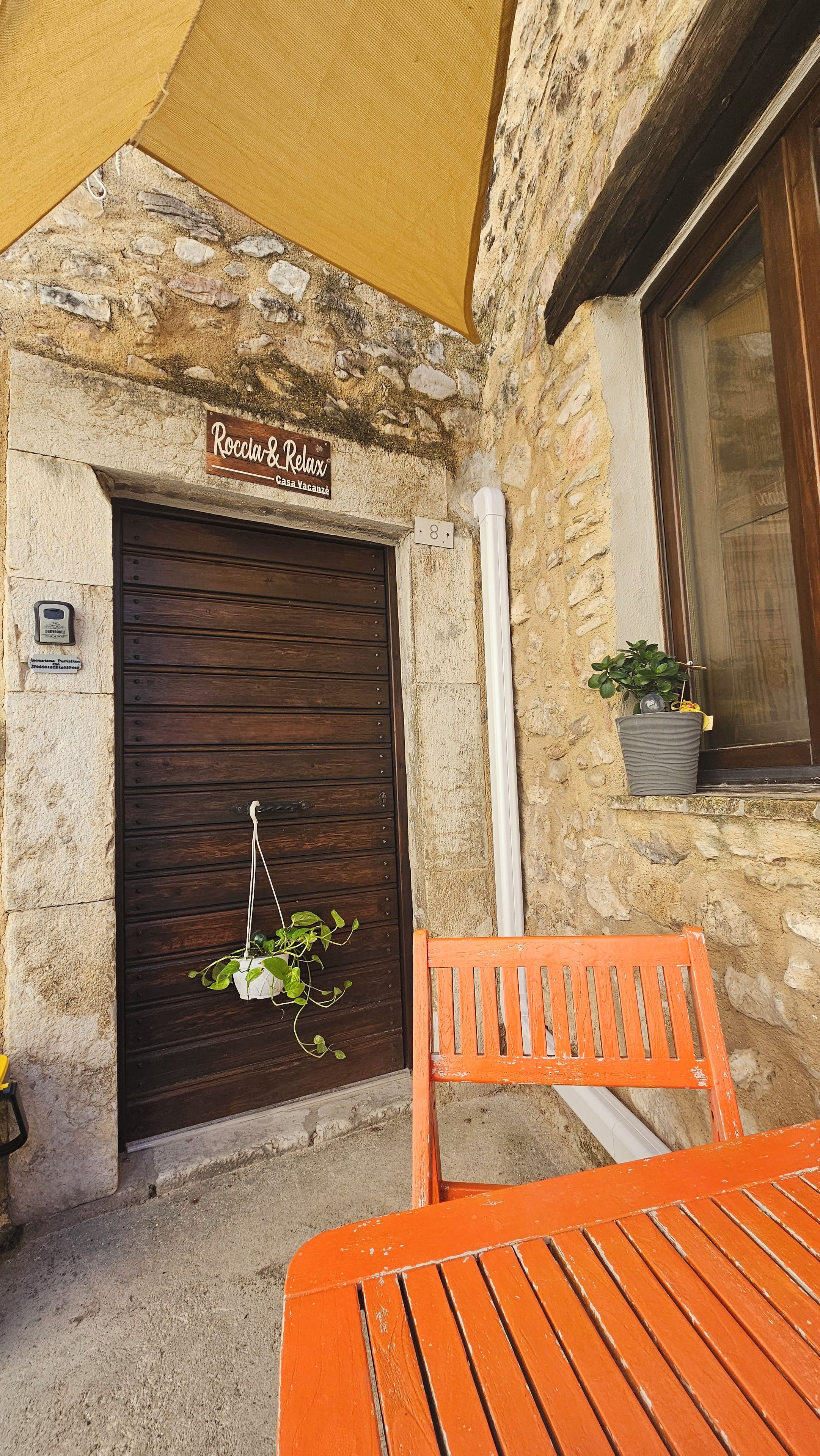 Un edificio rustico in pietra con una porta di legno con la scritta 'Roccia & Relax'.
