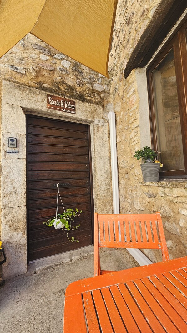 A rustic stone building with a wooden door labeled 'Roccia & Relax.'