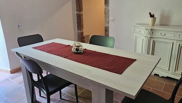 Ein Essbereich mit einem Holztisch, schwarzen Stühlen, einer roten Läuferbahn und einer Steinwand.