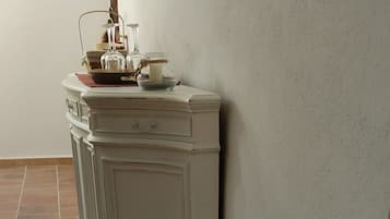 A corner of a room with a white cabinet against a wall, a tiled floor, and a pet water bowl on the floor.