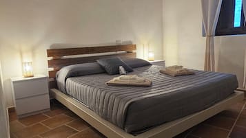 Una camera da letto con un letto, comodini, una lampada e una finestra con tende.