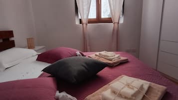 A bedroom with a bed, pillows, a window with curtains, and a wardrobe.