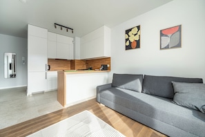 A modern kitchen with white cabinets, a wooden countertop, and a built-in coffee machine. - RentPlanet - Apartamenty  Wagonowa (Warszawa)