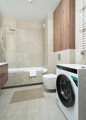 A modern bathroom with a shower, toilet, and washing machine. - RentPlanet - Apartamenty  Wagonowa (Warszawa)