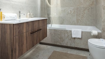 Un baño moderno con una bañera independiente, una ducha a ras de suelo y un tocador con espejo.
