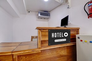 A hotel reception desk with a sign indicating it is company-serviced.