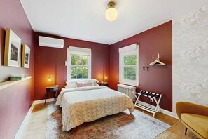 A bedroom with a double bed, two bedside tables, a radiator, a bench, and a chair. - Balsam House | Baraboo Hot Tub & Bluff Views (Baraboo)