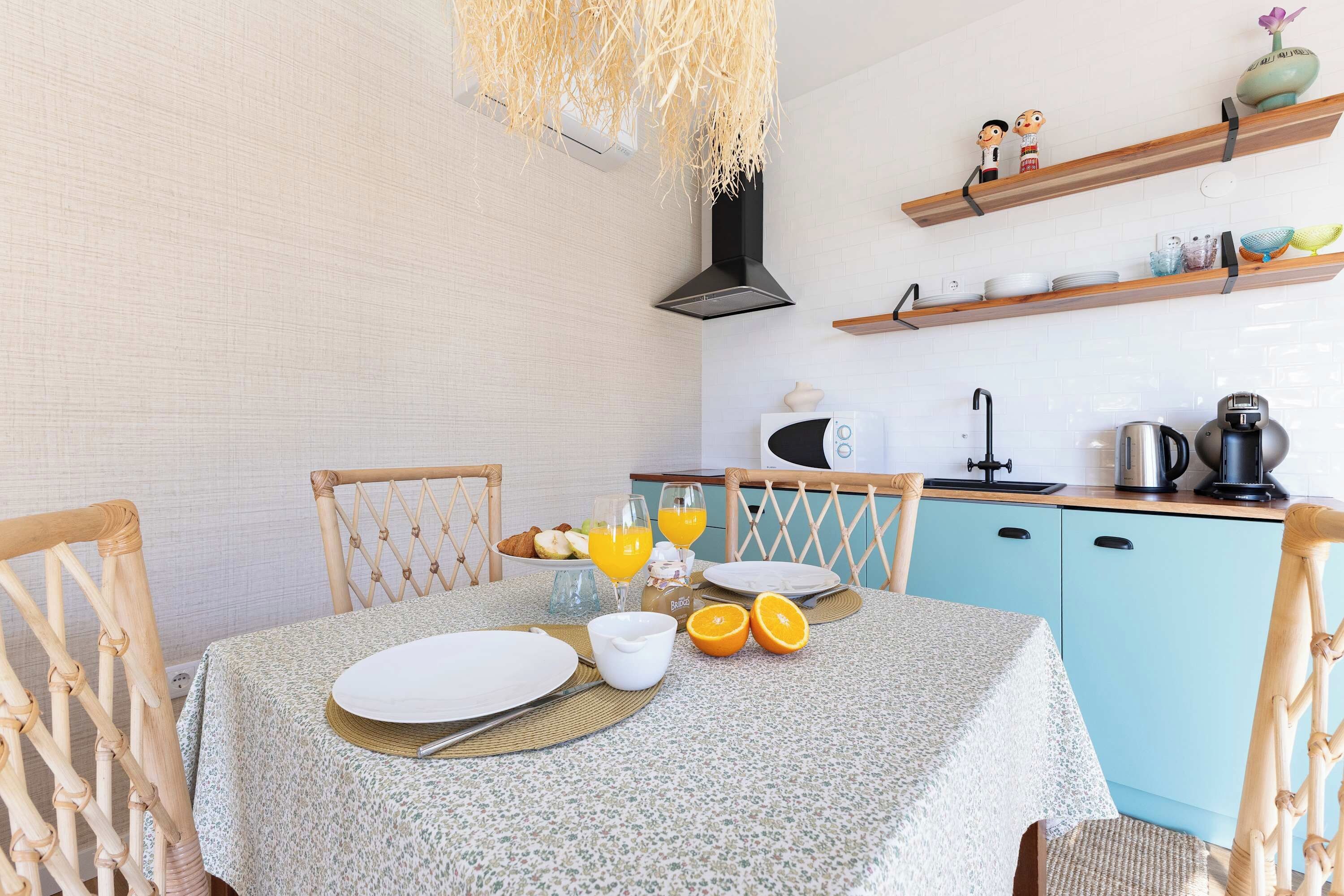 Een ontbijtarrangement met een tafel, stoelen en keukenapparatuur.