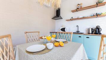 Een ontbijtarrangement met een tafel, stoelen en keukenapparatuur.