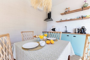 Una mesa con sillas y electrodomésticos de cocina para el desayuno.