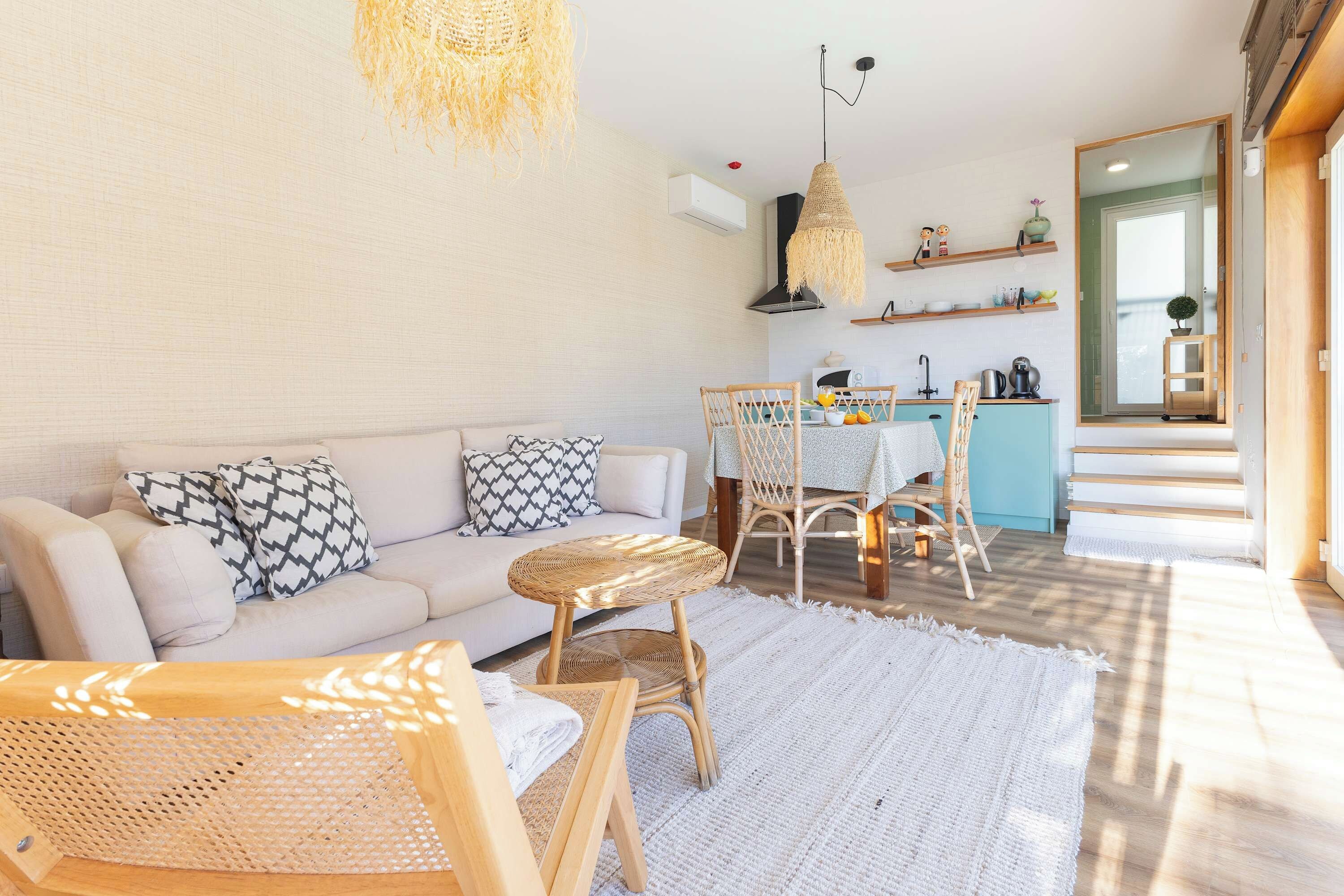 Una sala de estar moderna con sofá, sillas, una mesa de comedor y una zona de cocina con estanterías.