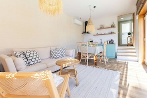 Una sala de estar moderna con sofá, sillas, una mesa de comedor y una zona de cocina con estanterías.