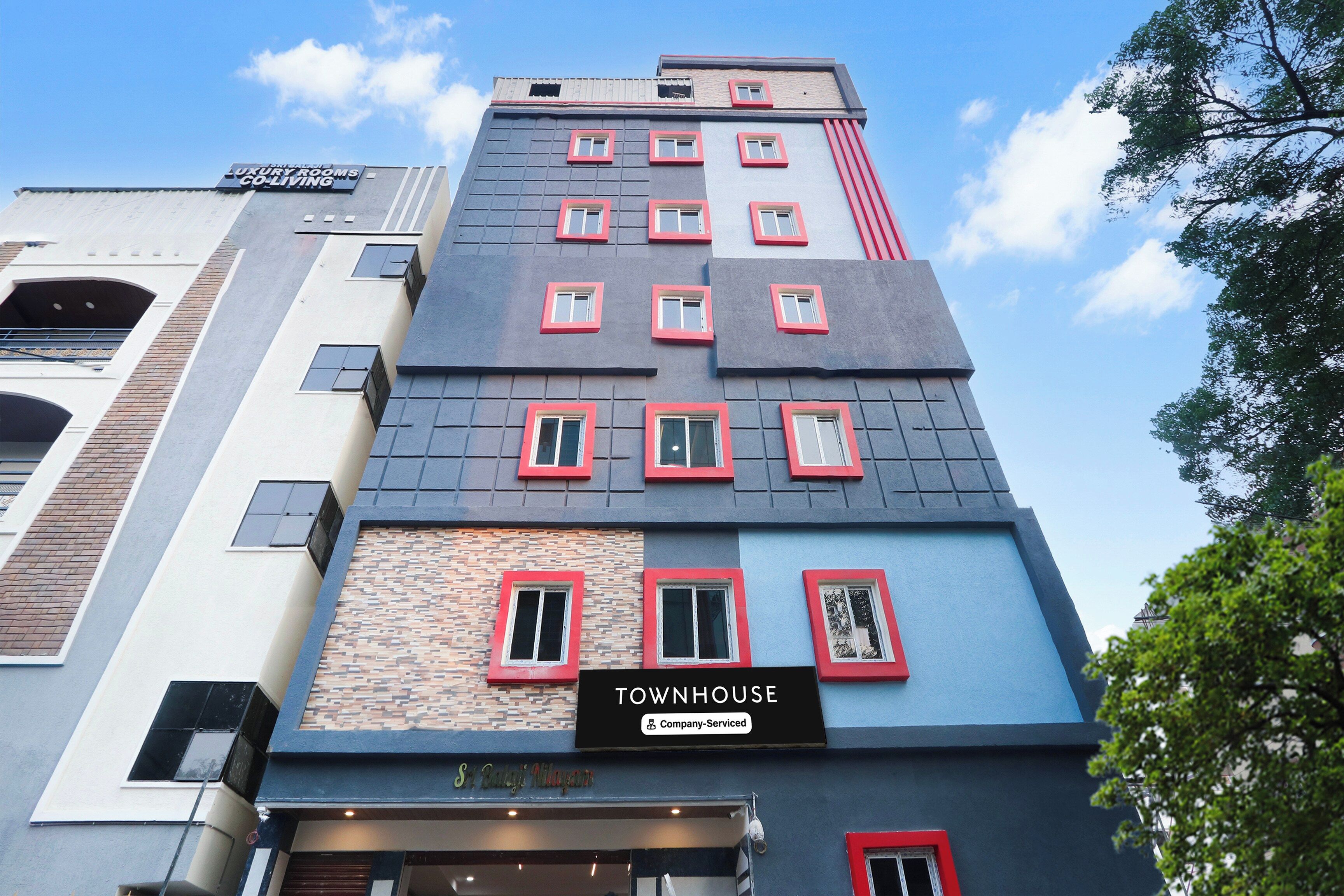 Un edificio de varios pisos con un cartel que indica 'TOWNHOUSE' y 'Luxury Rooms Co-Living'.