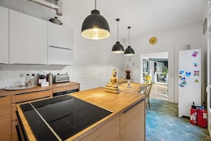 A modern kitchen with a wooden island, black appliances, and pendant lighting. - Pilon | Ground-Floor Apartment with Private Garden in Montmartre (Paris)