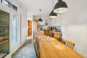 A modern kitchen with wooden cabinets, a central island, and pendant lighting. - Pilon | Ground-Floor Apartment with Private Garden in Montmartre (Paris)