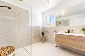 Un baño moderno con cabina de ducha de vidrio, tocador de madera y un espejo grande.