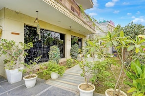 A reception area with a sign, potted plants, and a pathway leading to the entrance. - Townhouse Sector 47 Near Medanta (Gurugram)