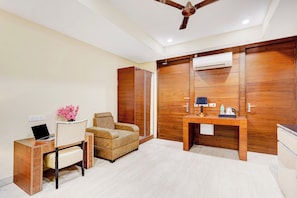 A hotel room with a desk, chair, sofa, and a wardrobe with a mirror. - Townhouse Sector 47 Near Medanta (Gurugram)