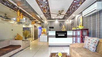 A hotel lobby with a reception desk, sofas, a coffee table, and decorative elements.