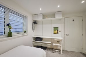 A bedroom with a bed, a window with blinds, a wardrobe, and a small mirror. - Host & Stay | Fish Quay View (Tynemouth)