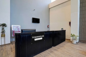 Un comptoir d’accueil portant l’inscription « TOWNHOUSE », avec un téléviseur à écran plat au-dessus, un extincteur fixé au mur et un panneau indiquant « RESTAURATION EXTERIEURE » sur le côté gauche.